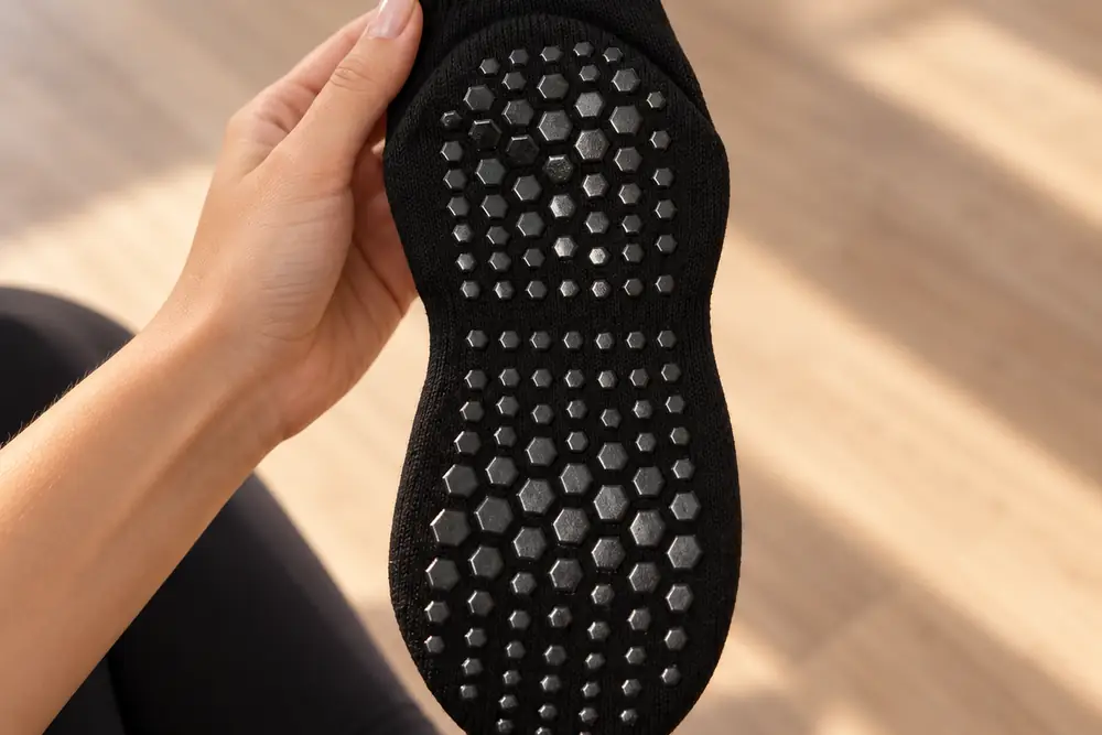 Close-up of the honeycomb silicone grip sole, sock turned inside out in a hand under raking light