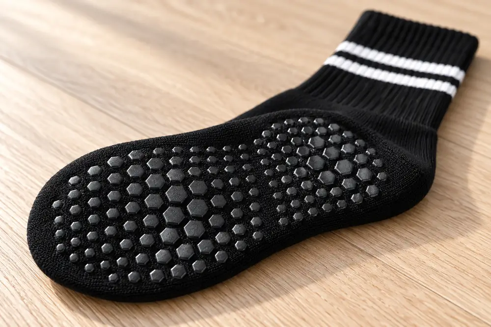 Sole of a grip sock seen from below on a wood floor, silicone dots in macro